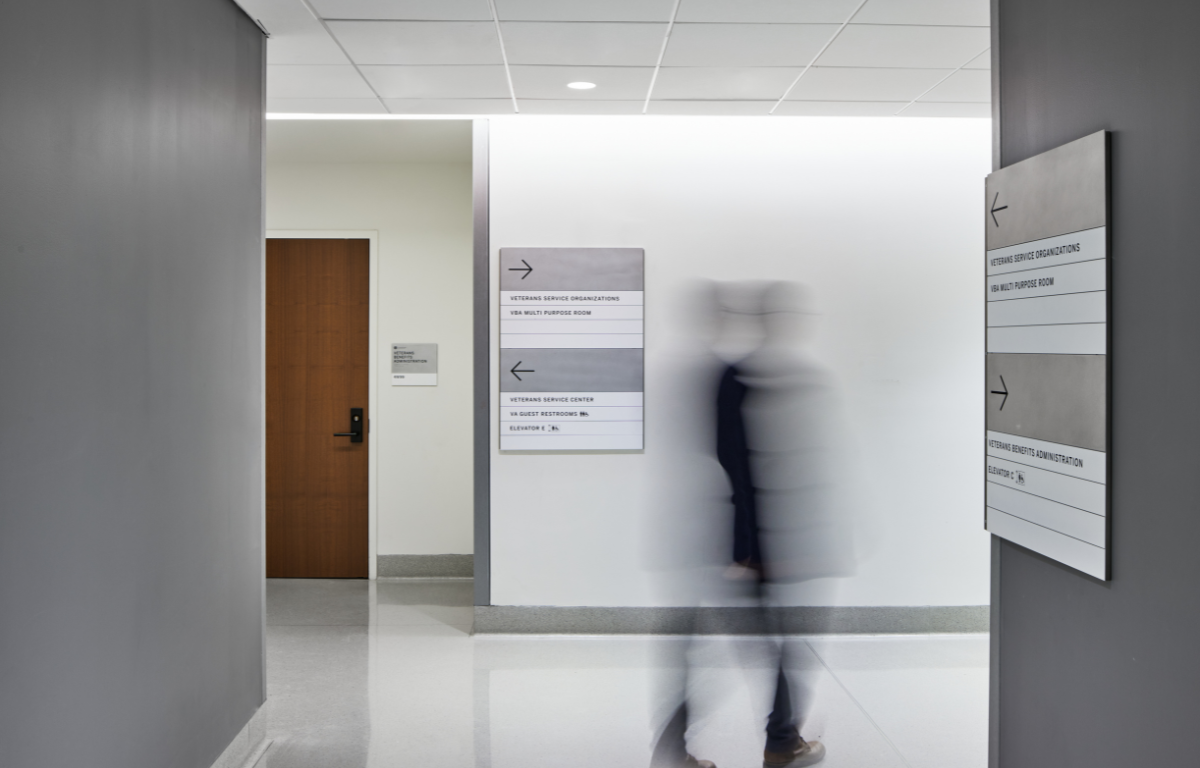 WorkplaceWayfinding Employee walks through hallway of workplace with directories on adjacent walls.